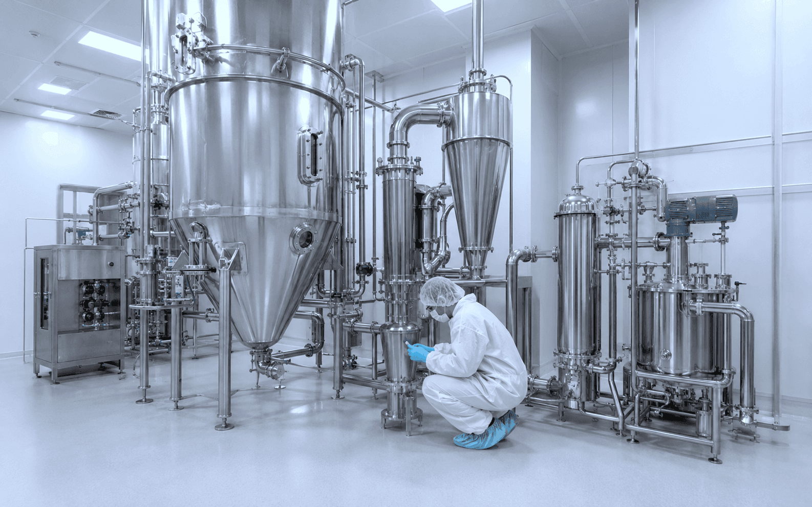 Operator working with pharmaceutical spray drying equipment in a cleanroom