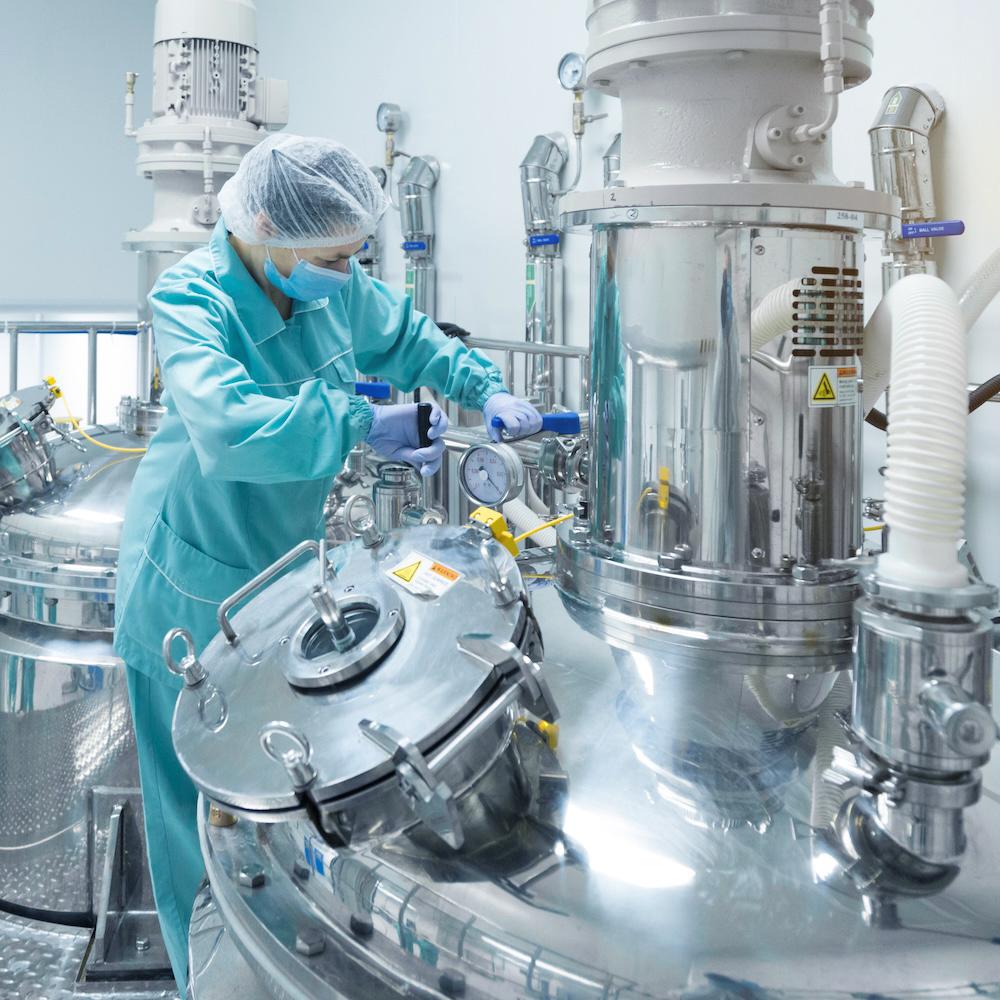 Technician working with large stainless steel pharmaceutical equipment